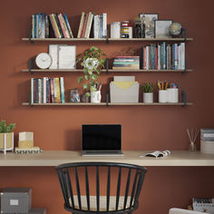 a laptop computer sitting on top of a wooden desk next to a bookshelf