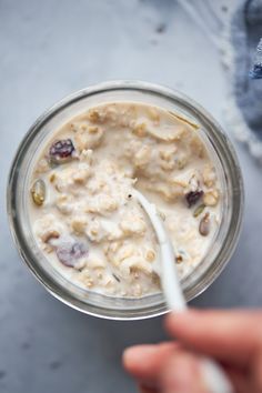 a person is holding a spoon over a bowl of oatmeal