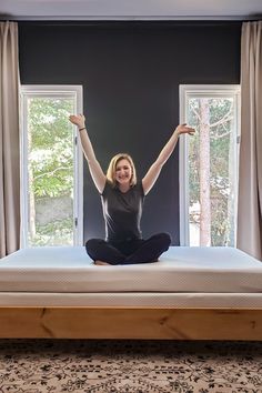 a woman sitting on top of a bed with her arms in the air