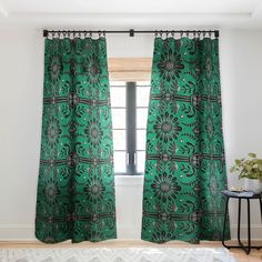 a green curtain hanging in front of a window next to a table with a potted plant