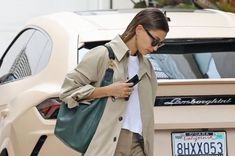 a woman is walking down the street while looking at her cell phone and holding a purse