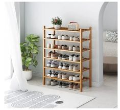 a wooden shoe rack with many pairs of shoes on it and a potted plant in the corner