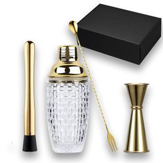 a glass bottle with a gold handle next to a black box and a golden spoon