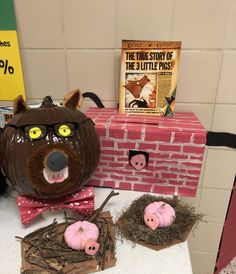 two fake pigs sitting next to each other in front of a brick wall with books on it