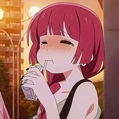 a woman with red hair drinking from a glass in front of a cityscape