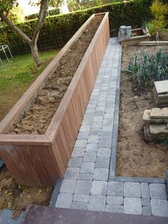 an outdoor garden area with brick walkway and raised planter box in the center, surrounded by landscaping equipment