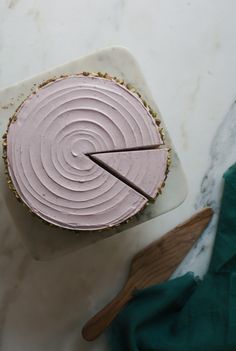 a cake with pink frosting sitting on top of a white plate next to a knife