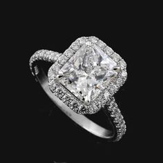 an engagement ring with a princess cut diamond surrounded by pave diamonds on a black background