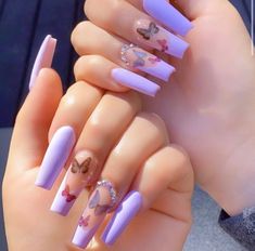 a woman's hands with purple nail polish and butterfly designs on their nails,