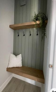 a wooden bench sitting in the corner of a room next to a wall with hooks on it