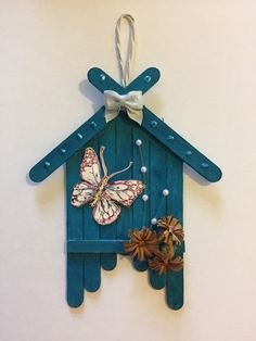 a blue birdhouse shaped like a house with a butterfly on it