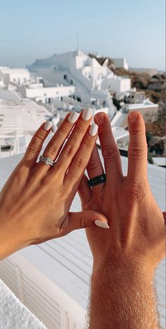 two hands reaching up towards each other with white buildings in the background