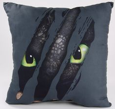 a pillow with two green eyes on the front and one in the back that is black