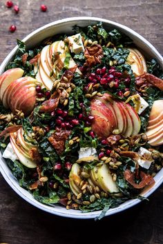 an apple and kale salad in a white bowl on a wooden table with nuts