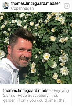 a man is smiling in front of some white flowers with the caption thomas lindenegard madsen