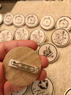 a person holding a small wooden button in front of some buttons on a cloth covered surface