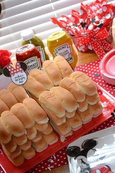 a table topped with lots of sandwiches and condiments for mickey mouse birthday party