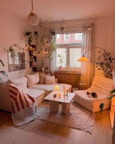 a living room filled with white furniture and lots of plants on the windows sill