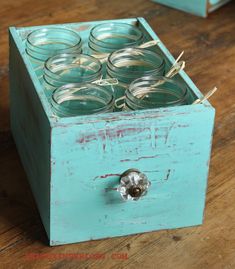 a blue box filled with glass jars sitting on top of a wooden table