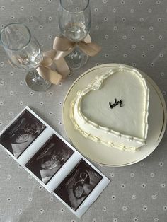 a heart shaped cake sitting on top of a table next to wine glasses and photos