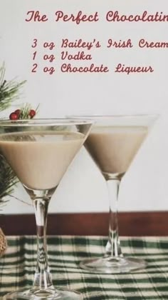 two martini glasses sitting on top of a checkered table cloth next to a pine tree