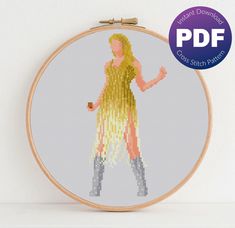 a cross - stitch pattern of a woman in yellow dress and boots, with text underneath