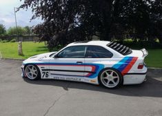 a white sports car with colorful stripes parked in a parking lot next to some trees