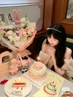 a woman sitting at a table with a cake and flowers