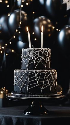 a spider web cake with candles in it on a table next to some black balloons