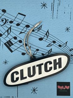 a black and white sign that says clutch with musical notes in the sky behind it