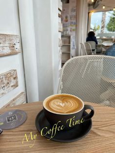 a cup of coffee sitting on top of a wooden table