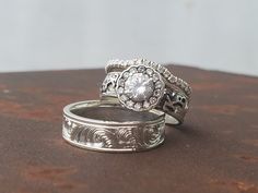 two wedding rings sitting on top of each other with diamonds in the center and sides