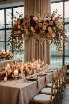 a long table with candles and flowers on it is set up for a formal dinner