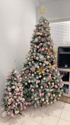 two decorated christmas trees in front of a tv