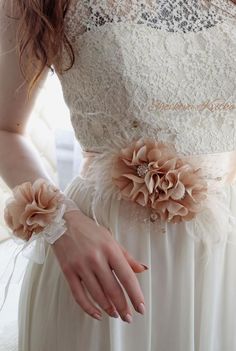 a woman in a white dress with flowers on her wrist and hands holding onto the belt