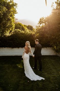 a bride and groom standing in the grass