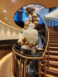 the staircase is decorated with gold and white balloons