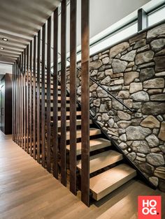 a stone wall and wooden stairs in a modern house with wood flooring on both sides