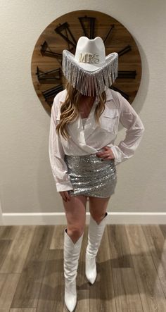 a woman in silver sequin skirt and white cowboy hat posing for the camera with her hands on her hips