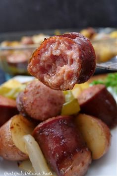 a close up of food on a plate with potatoes and meats in the background