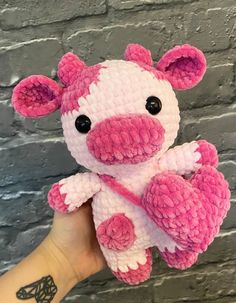 a pink and white crocheted stuffed animal in front of a gray brick wall