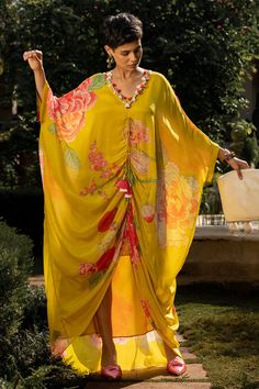 Lime yellow ruched kaftan with floral print, front slit and drawstring tie-up with cowrie shells and tassels. Comes with slip.
Components: 2
Pattern: Printed
Type Of Work: Floral Patterns
Neckline: V-Neck
Sleeve Type: Batwing Sleeves
Fabric: Crepe
Color: Yellow
Other Details: 
Tassel tie-up
Note: Bag held by the model is not for sale
Occasion: Resort - Aza Fashions Luxury Kaftan, Paulmi And Harsh, Kaftan Pattern, Blouse Yoke, 1950’s Fashion, Kaftan Designs, Poolside Fashion, Lime Yellow, Cowrie Shells