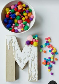 the letters m and m are decorated with pom - poms in different colors