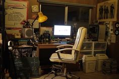 a computer desk with a chair, monitor and many other office items on it in front of a window