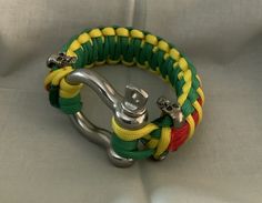 a green, yellow and red paracorte bracelet with a metal hook on it