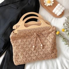 a crocheted purse sitting on top of a bed next to a vase with flowers