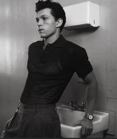 a black and white photo of a man standing in front of a sink with his hands on his hips