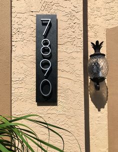 a house number sign mounted to the side of a building with a pineapple on it