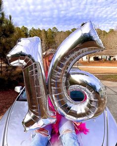 a woman sitting in the back of a car with an air filled number balloon