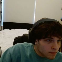 a young man wearing headphones sitting in front of a bed